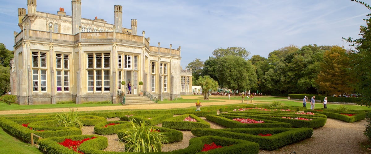 A historic building with a formal garden and a bench.