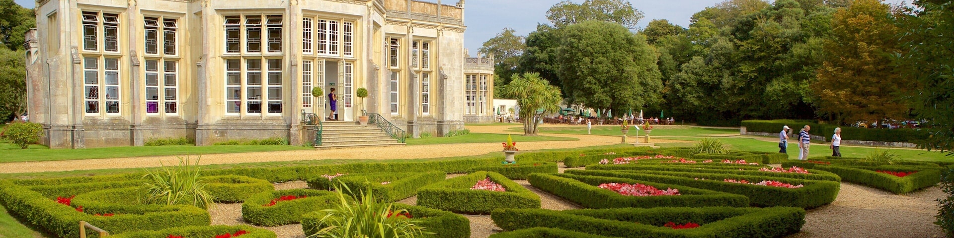 A historic building with a formal garden and a bench.