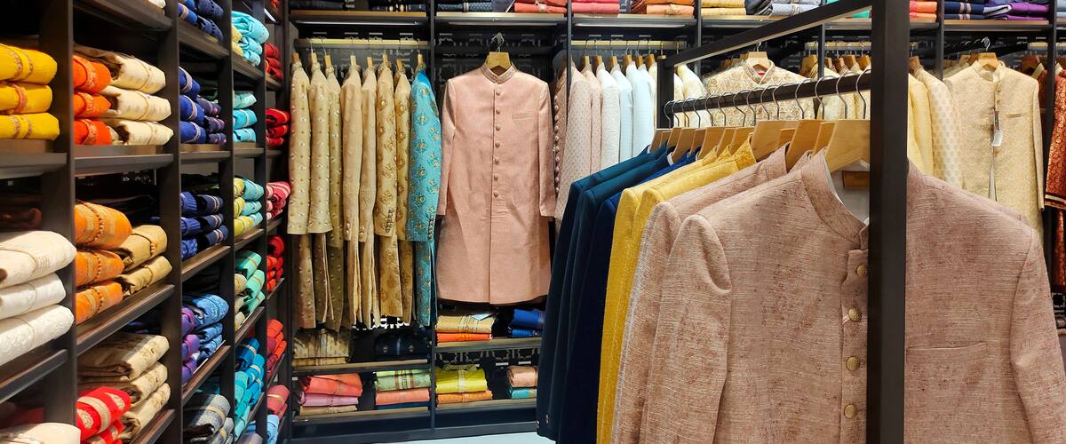 A clothing store with shelves of folded fabrics and racks of garments.