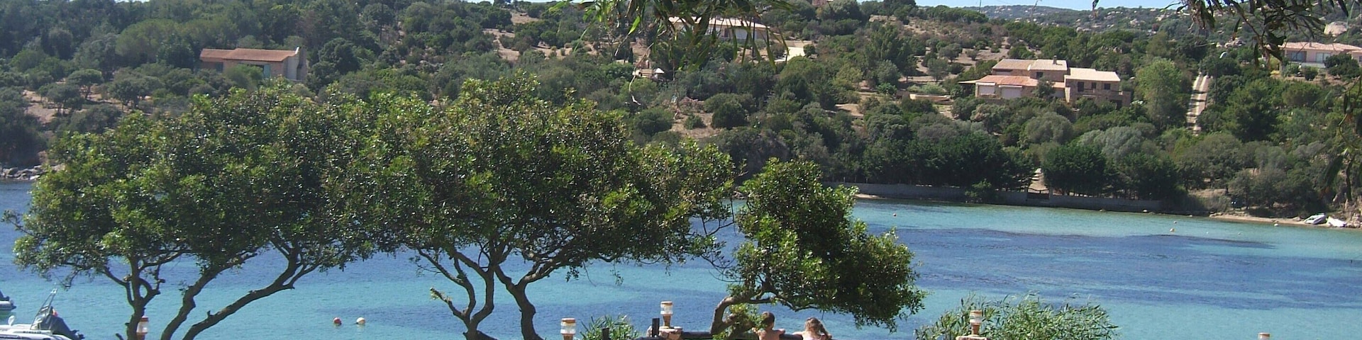 A coastal landscape with a clear view of the sea, a grassy area, and a stone fence.