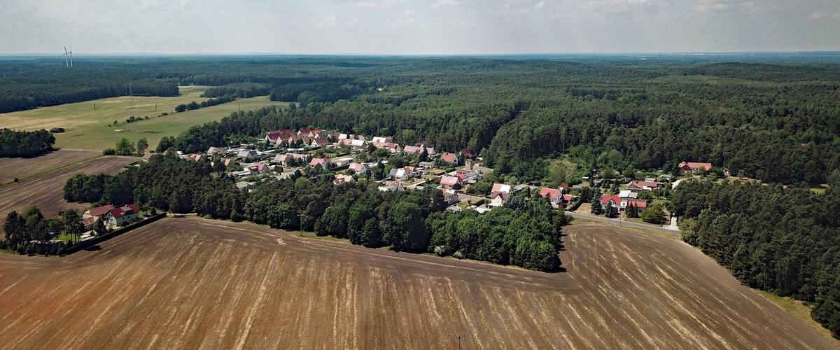 An aerial view of a rural village surrounded by fields and forests.