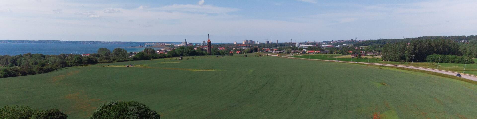 Aerial view of a field filled with poppy flowers in full bloom with the small village of Råå, Sweden in the background.