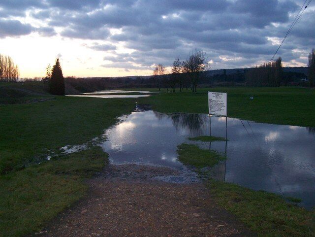 Un campo inundado con un cartel y un sendero que lo atraviesa.