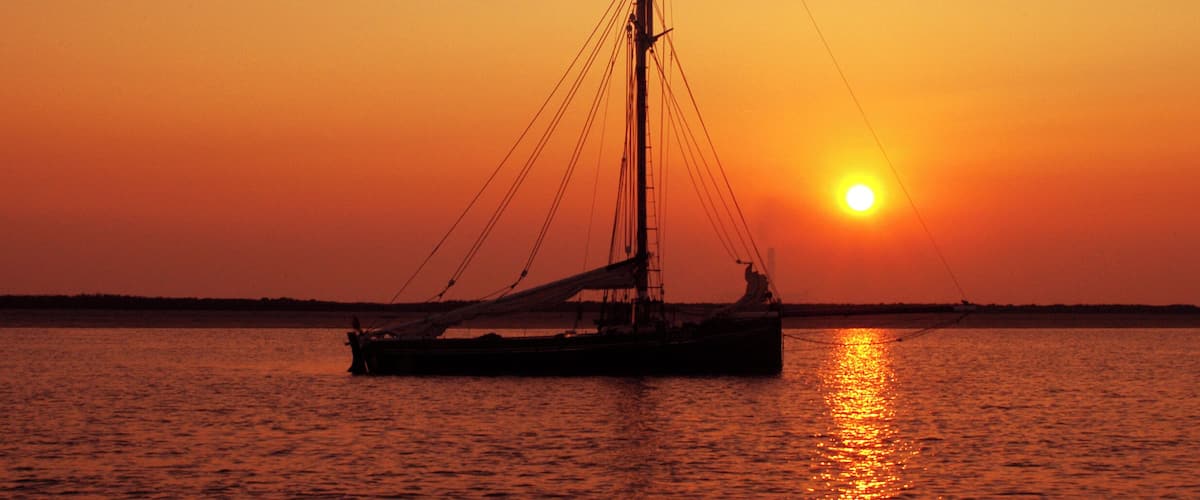 A sailboat on calm water during sunset.