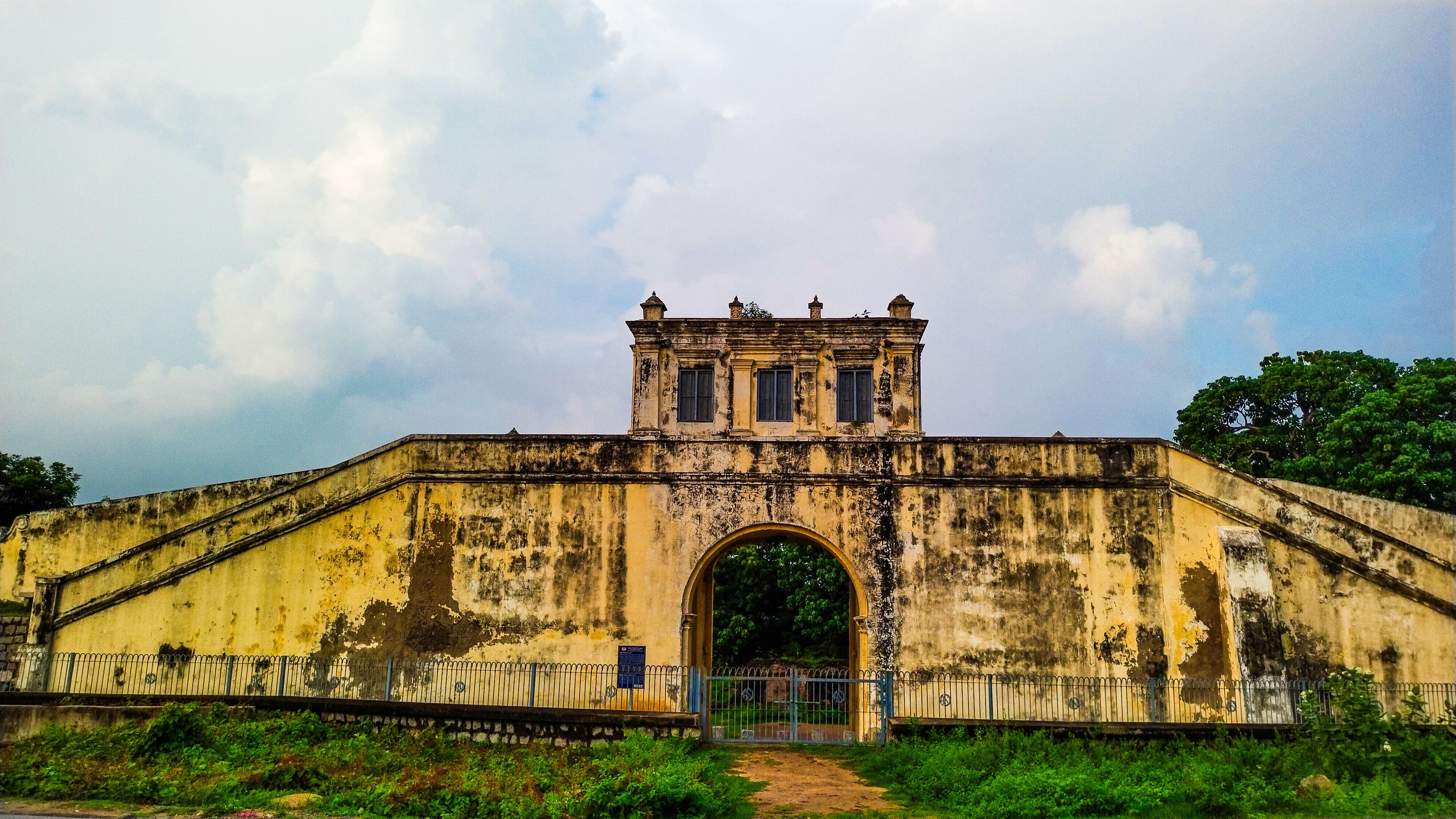 An old, weathered bridge with a central archway and a small tower on top.