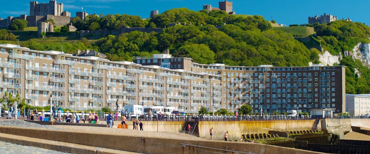 Dover Beach featuring a sandy beach and heritage architecture as well as a large group of people
