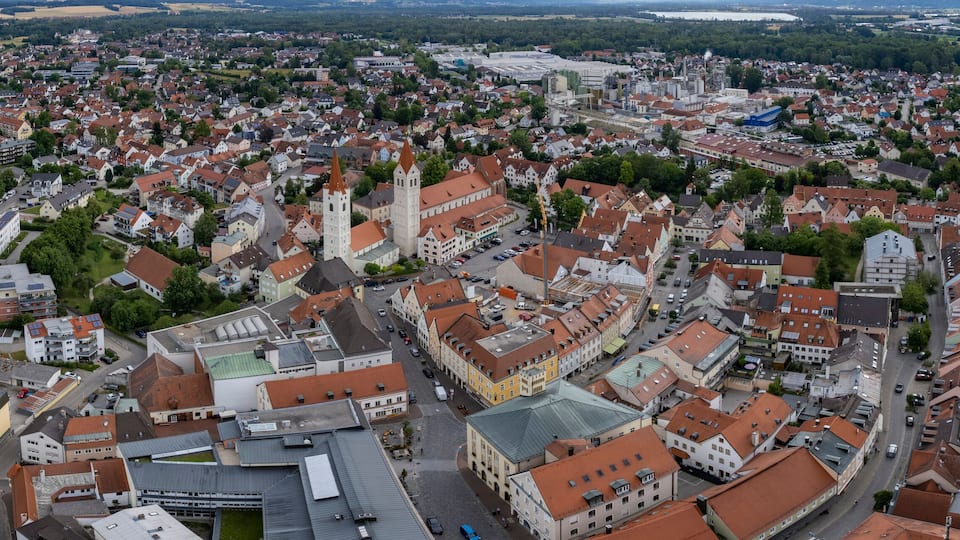 Eine geschäftige Stadt mit historischen Gebäuden, einer markanten Kirche und einem großen Gewässer im Hintergrund.