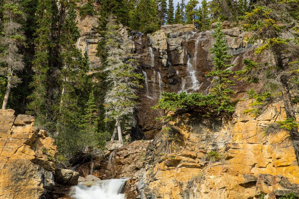 A waterfall cascading down a rocky cliff surrounded by dense forest.