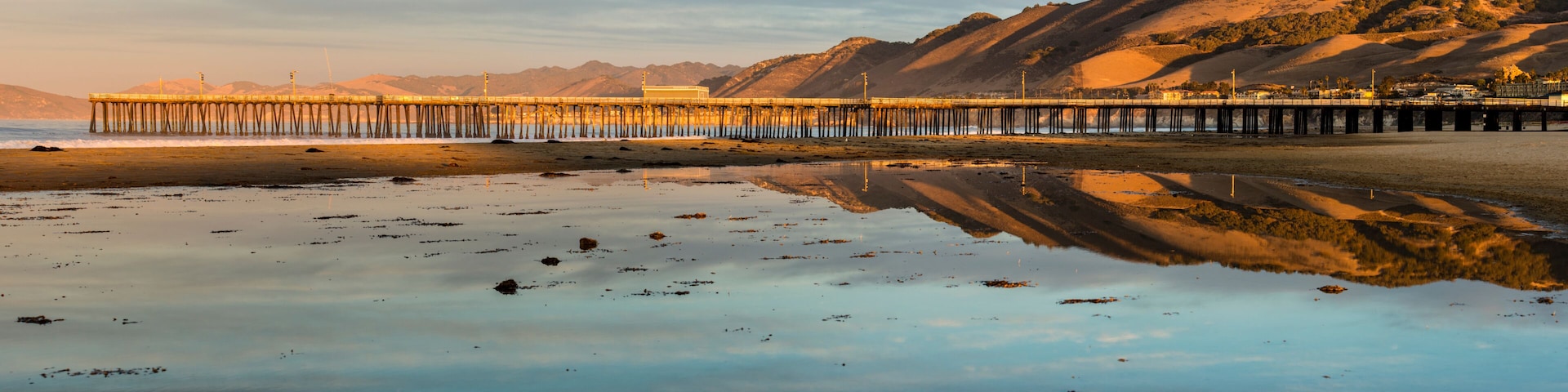 Scenic view of pier on beach during sunrise