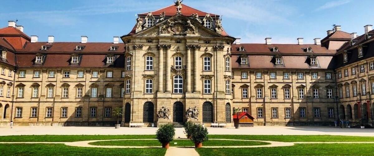 A grand historical building with symmetrical architecture, a central courtyard, and statues.