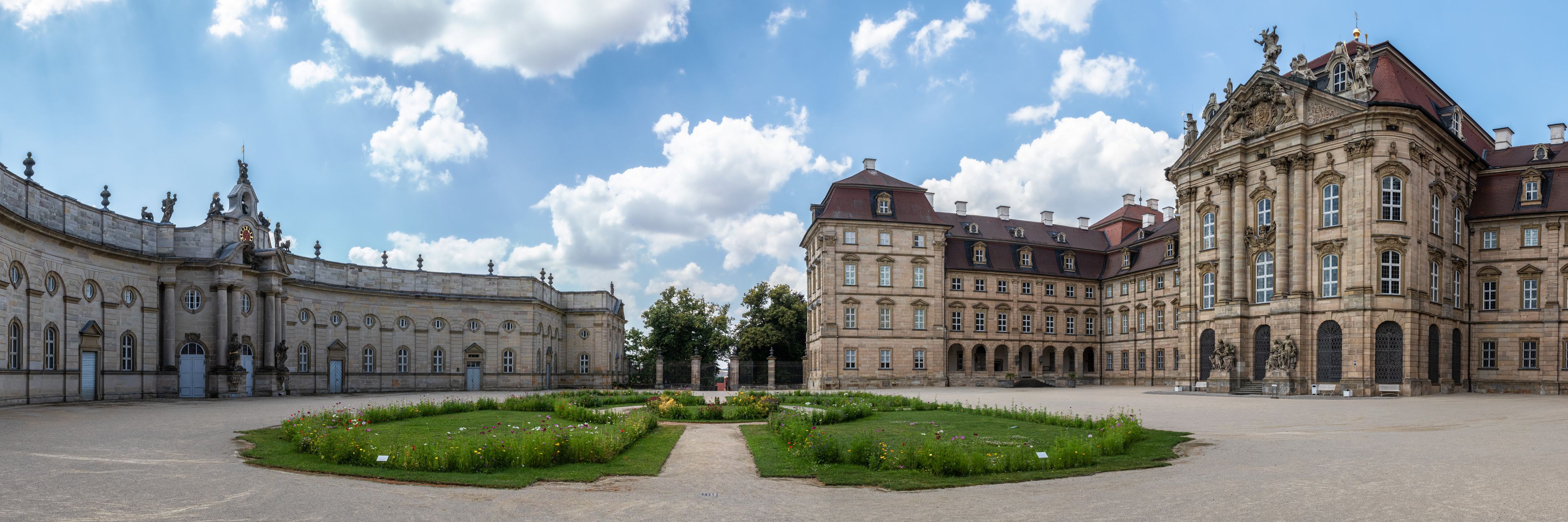Une vaste cour d’honneur à l’architecture classique, agrémentée de bâtiments richement décorés et d’un jardin bien entretenu.