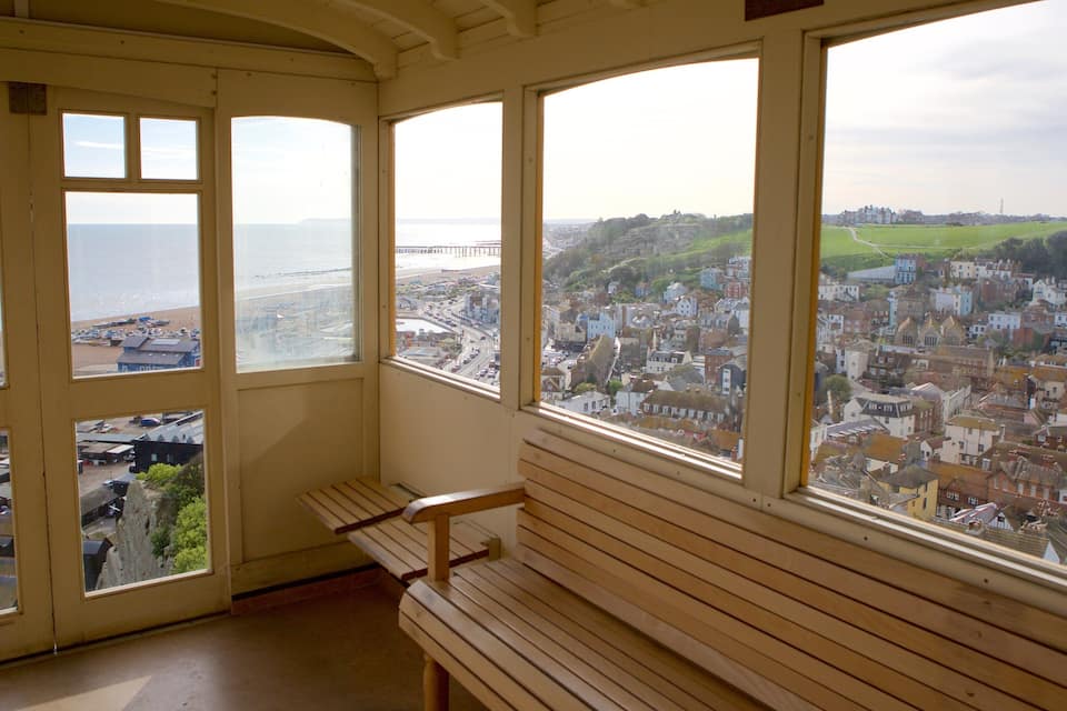A room with large windows overlooking a coastal town and a bridge.