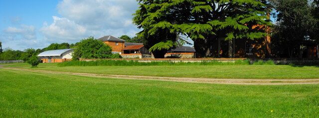 Stacey Hill Farm, Stacey Avenue, Wolverton, Milton Keynes, Buckinghamshire. Built as a model farm in 1848, now converted into Milton Keynes Museum. The farmhouse is behind the large cedar tree on the right of the photo. Across the middle of the view is the retaining wall of a ha-ha. The modern building on the left houses a restored tramcar that used to run between Stony Stratford and Wolverton.