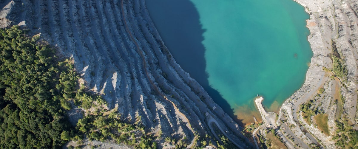 Vue aérienne d’une vaste étendue d’eau circulaire, entourée de formations rocheuses en terrasses.