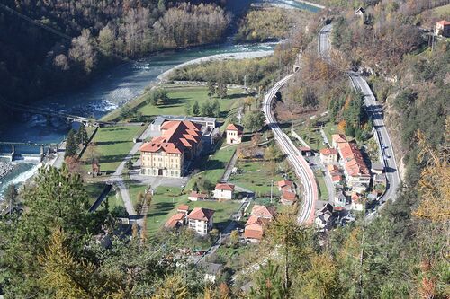 A river winding through a town with buildings and a bridge.