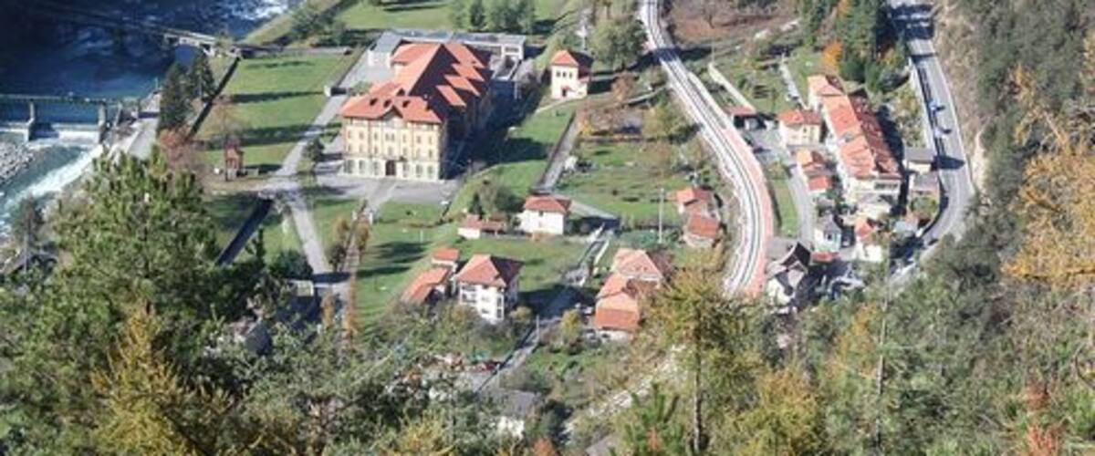 A river winding through a town with buildings and a bridge.