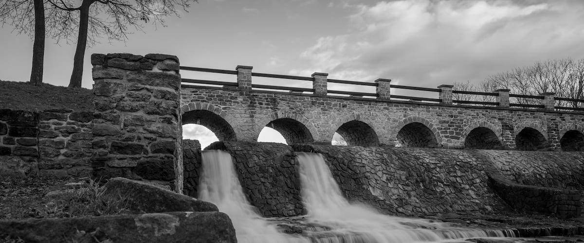 Bridge and river Rokytka in Dolni Pocernice, Prague, Czech republic, black and white
