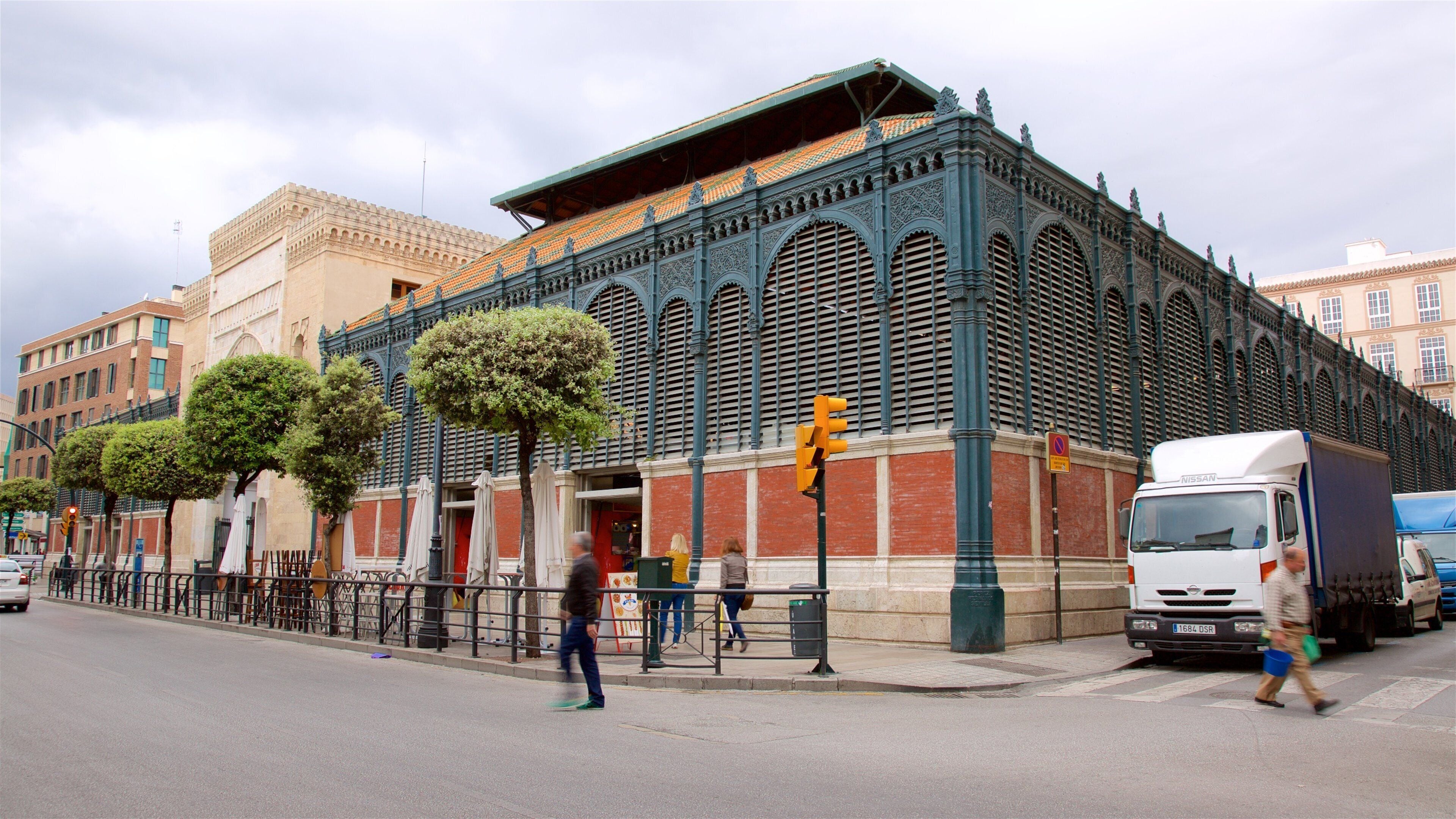 A historic building with ornate architecture, a street with pedestrians, and a parked truck.