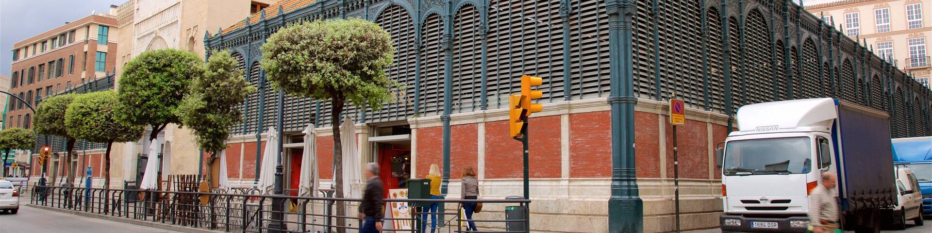 Un edificio histórico con arquitectura ornamentada, una calle con peatones y un camión estacionado.