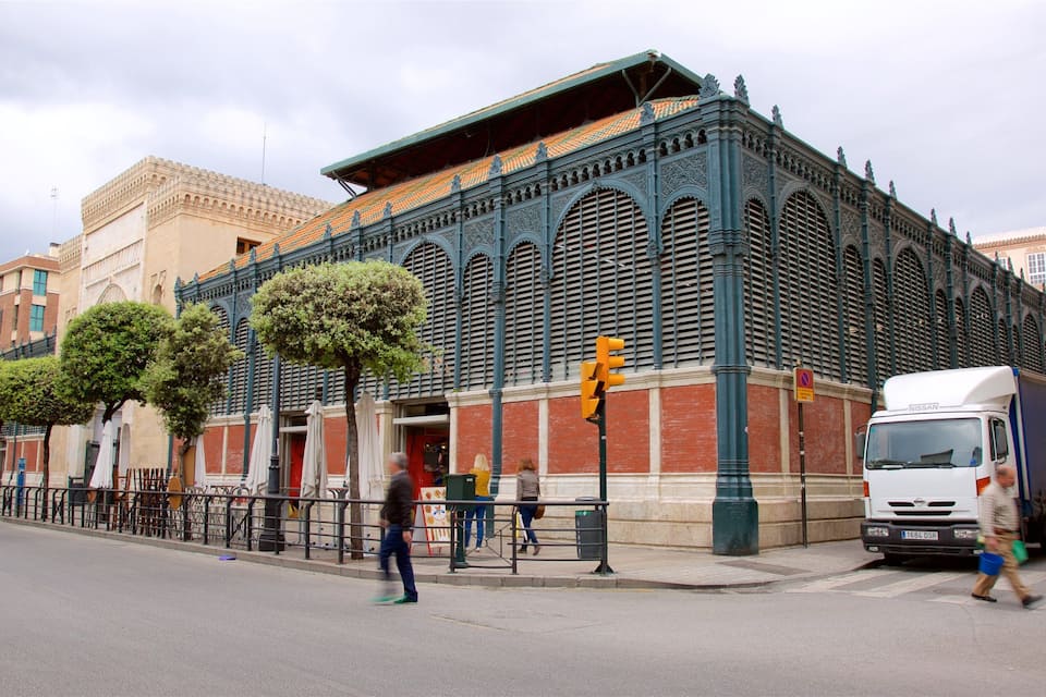Un edificio histórico con arquitectura ornamentada, una calle con peatones y un camión estacionado.