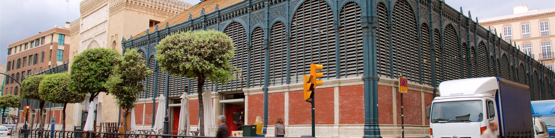 A historic building with ornate architecture, a street with pedestrians, and a parked truck.