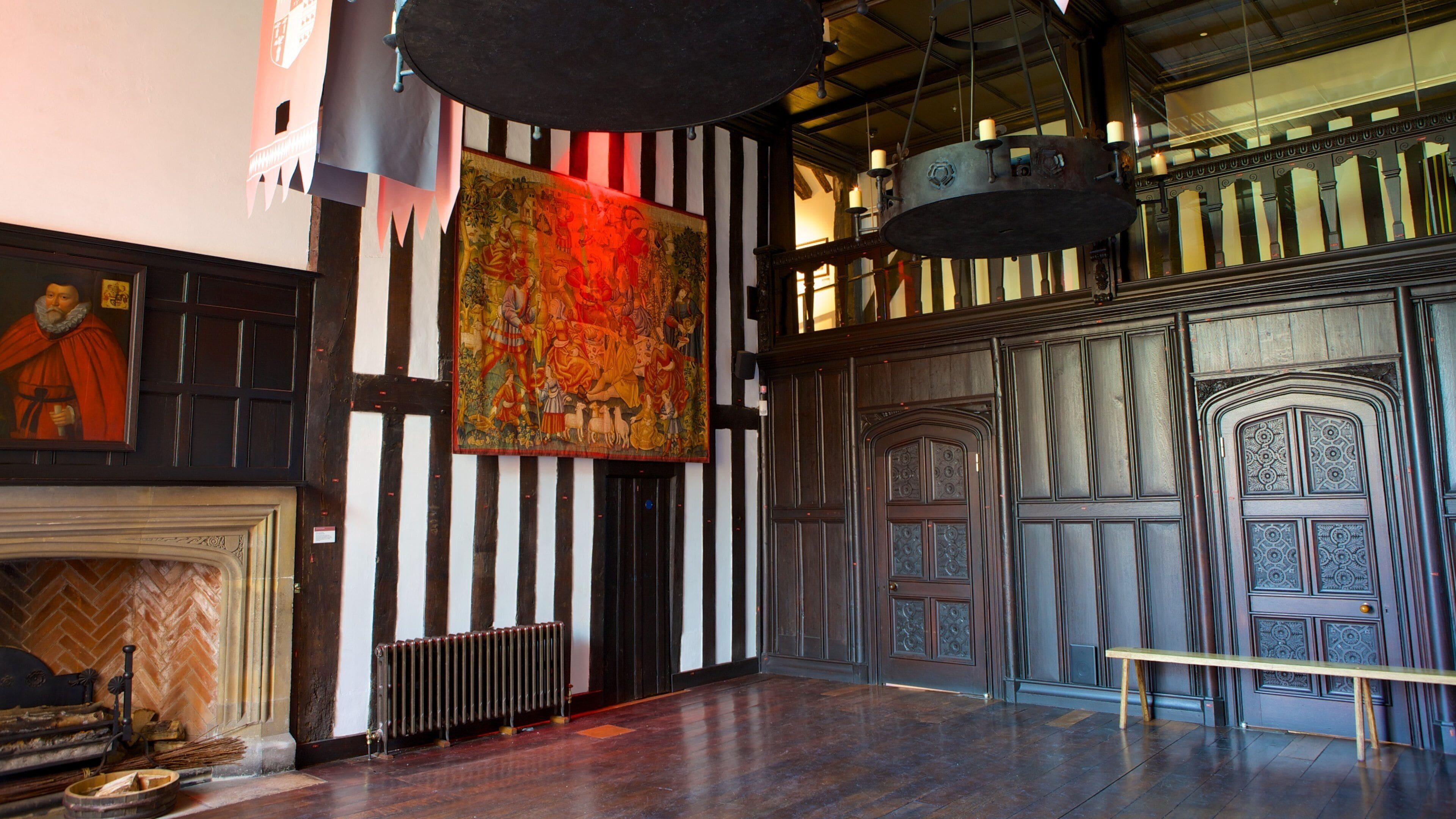 A room with a fireplace, a large tapestry, and a wooden door with intricate designs.