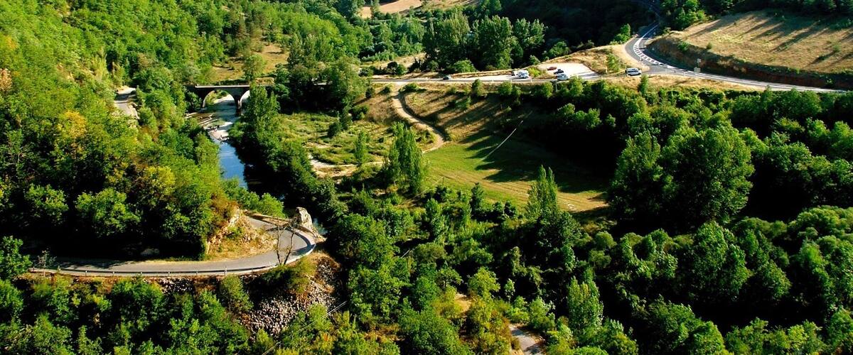 A valley with a winding road, a bridge, and a river.