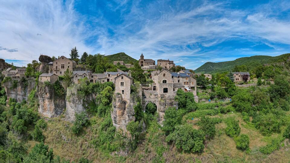 A historic stone castle perched on a cliff surrounded by lush greenery.
