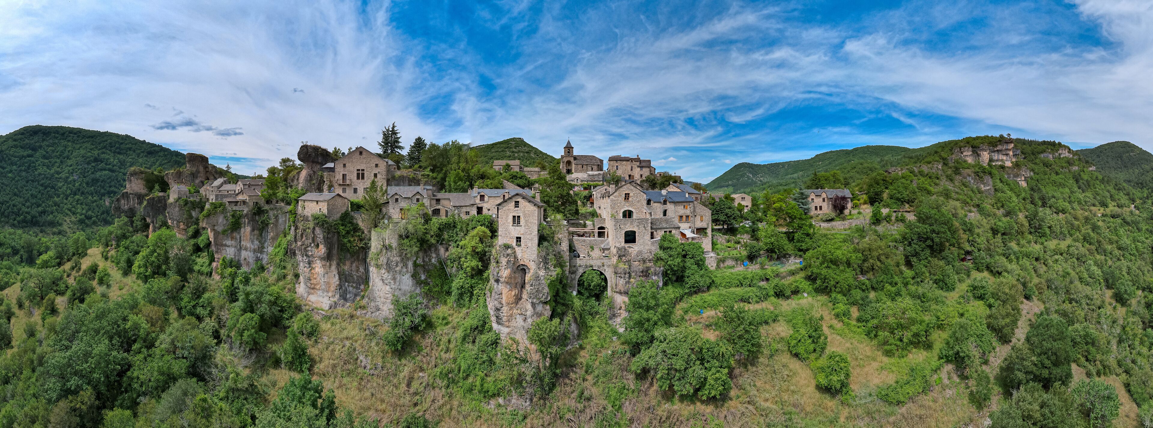 A historic stone castle perched on a cliff surrounded by lush greenery.
