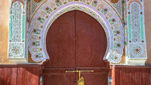 Traditional Moroccan style design of an ancient wooden entry door. In the old Medina. Typical, old, brown intricately carved, studded, Moroccan riad door in Meknes, Morocco.