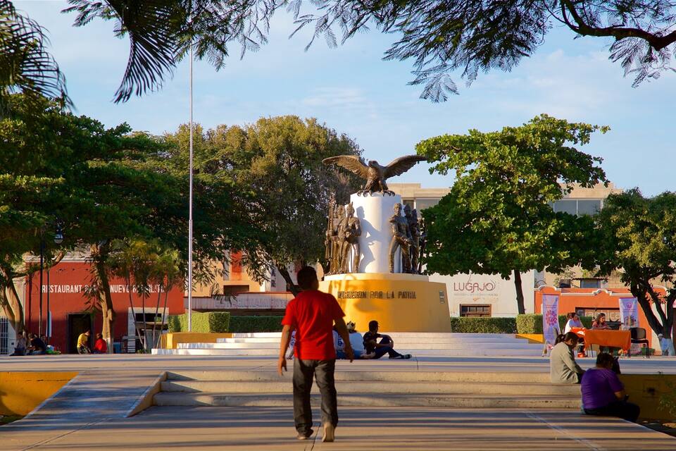 A statue of an eagle on a pedestal, surrounded by trees and people.