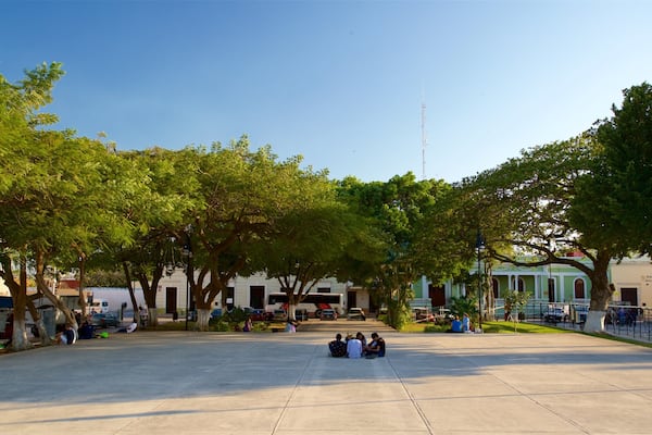 A spacious public square with trees, benches, and people sitting.