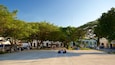 A spacious public square with trees, benches, and people sitting.