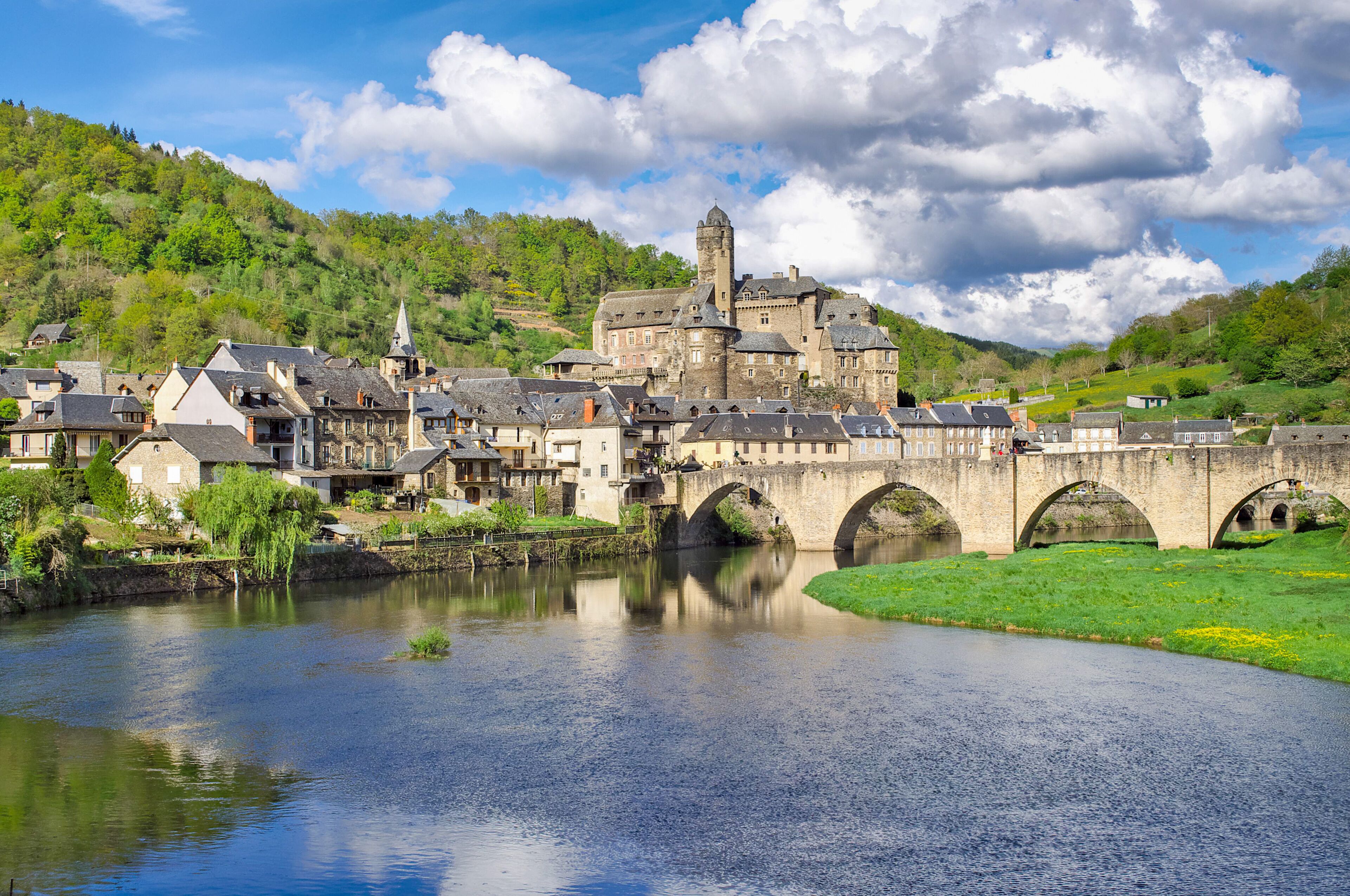 A historic town with a river, a bridge, and a castle-like building.