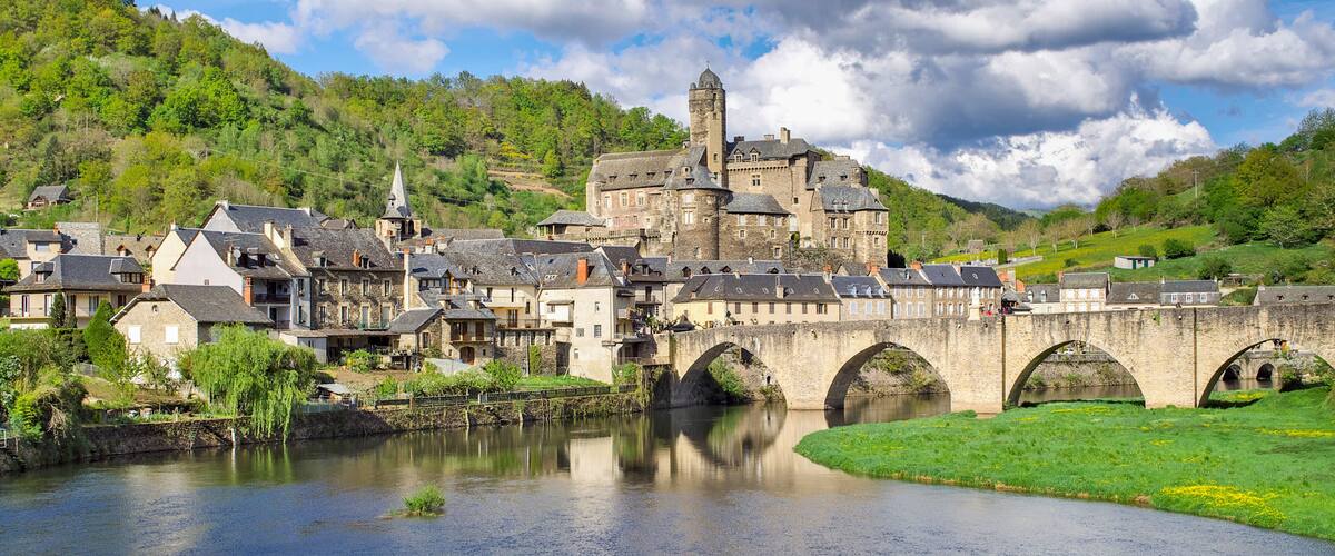 A historic town with a river, a bridge, and a castle-like building.