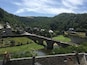 A stone bridge over a river, surrounded by lush greenery and historic buildings.