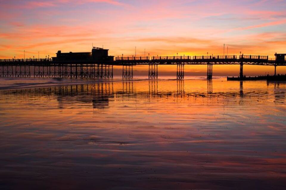 Un muelle se adentra en un cuerpo de agua tranquilo al atardecer.