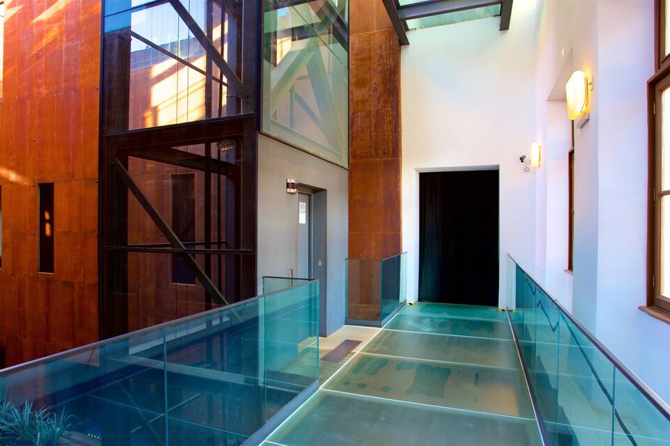 Un interior modern amb baranes de vidre, panells de fusta i una escala.