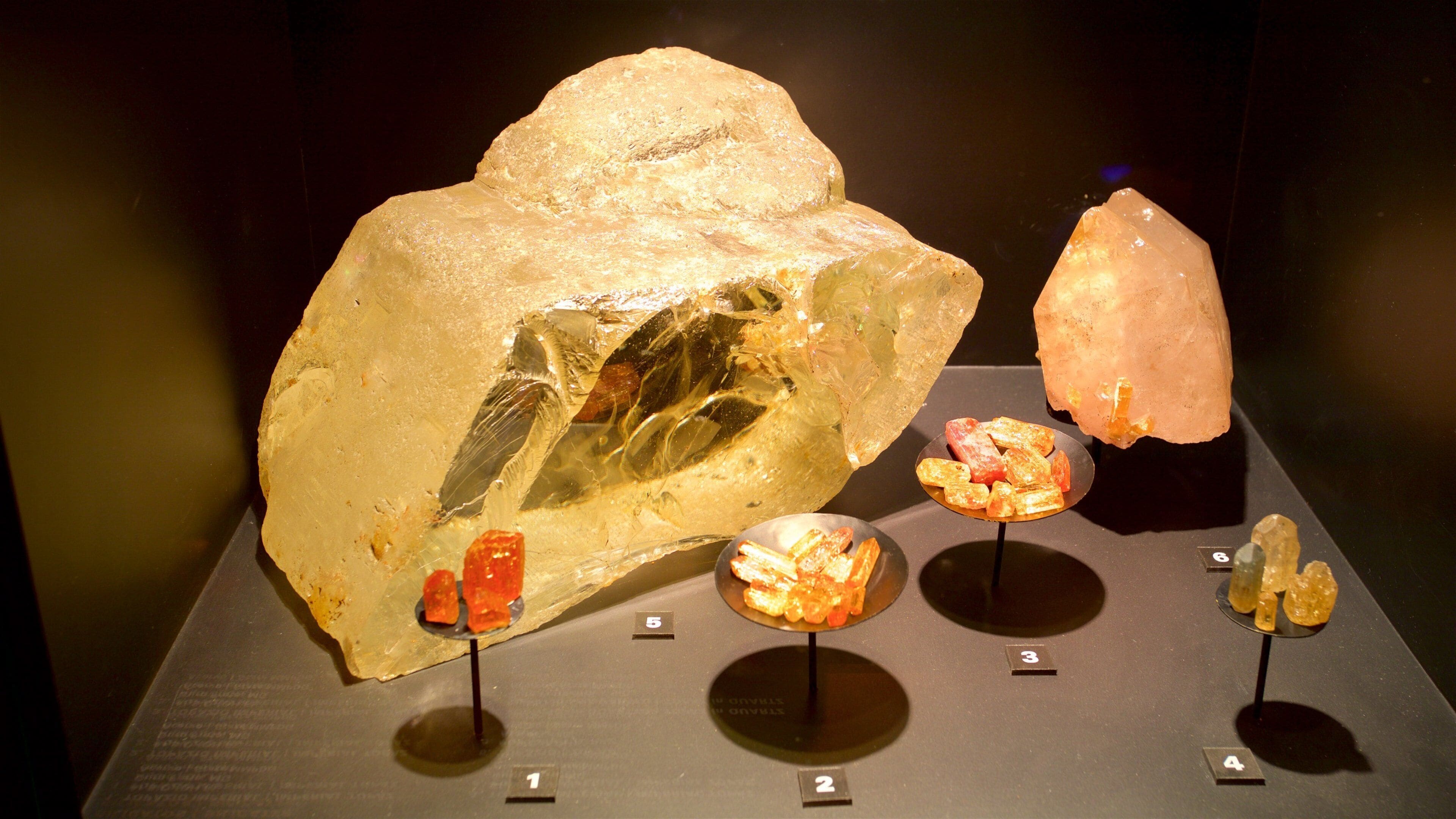 A display of various mineral specimens, including a large quartz crystal and smaller pieces of amber and other minerals.