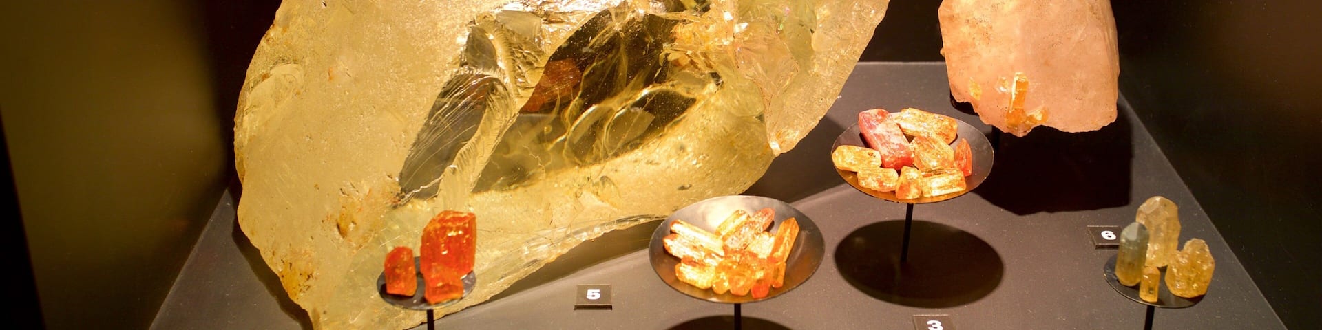 A display of various mineral specimens, including a large quartz crystal and smaller pieces of amber and other minerals.