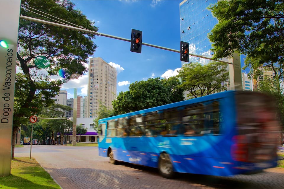 A blue bus on a city street with traffic lights and a sign reading "Praça Diogo de Vasconcelos".