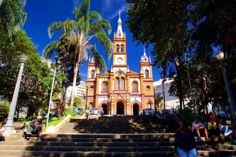 A historic church with a clock tower, surrounded by palm trees and steps leading up to it.