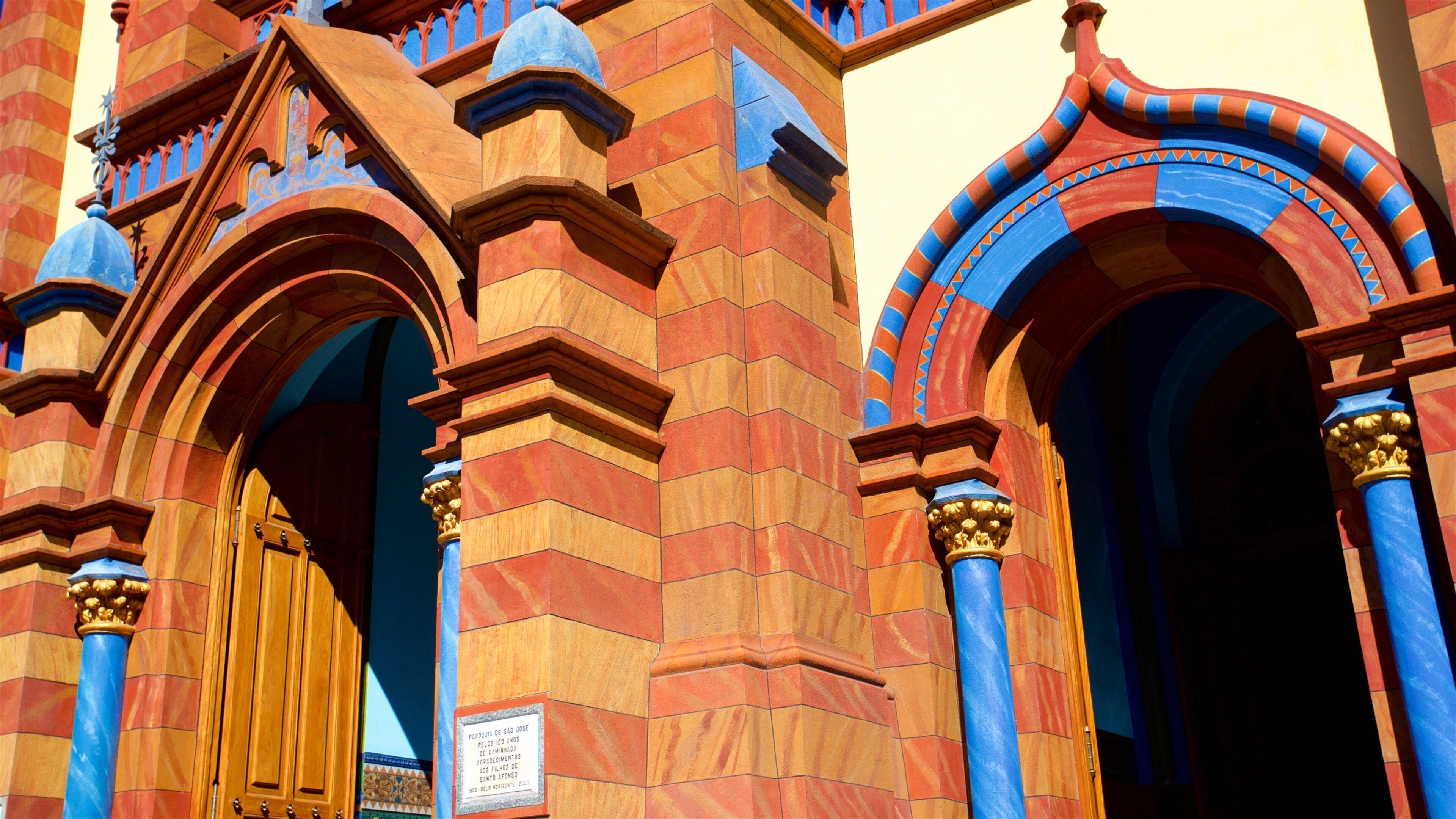 A building with red and blue brickwork, ornate arches, and golden columns.
