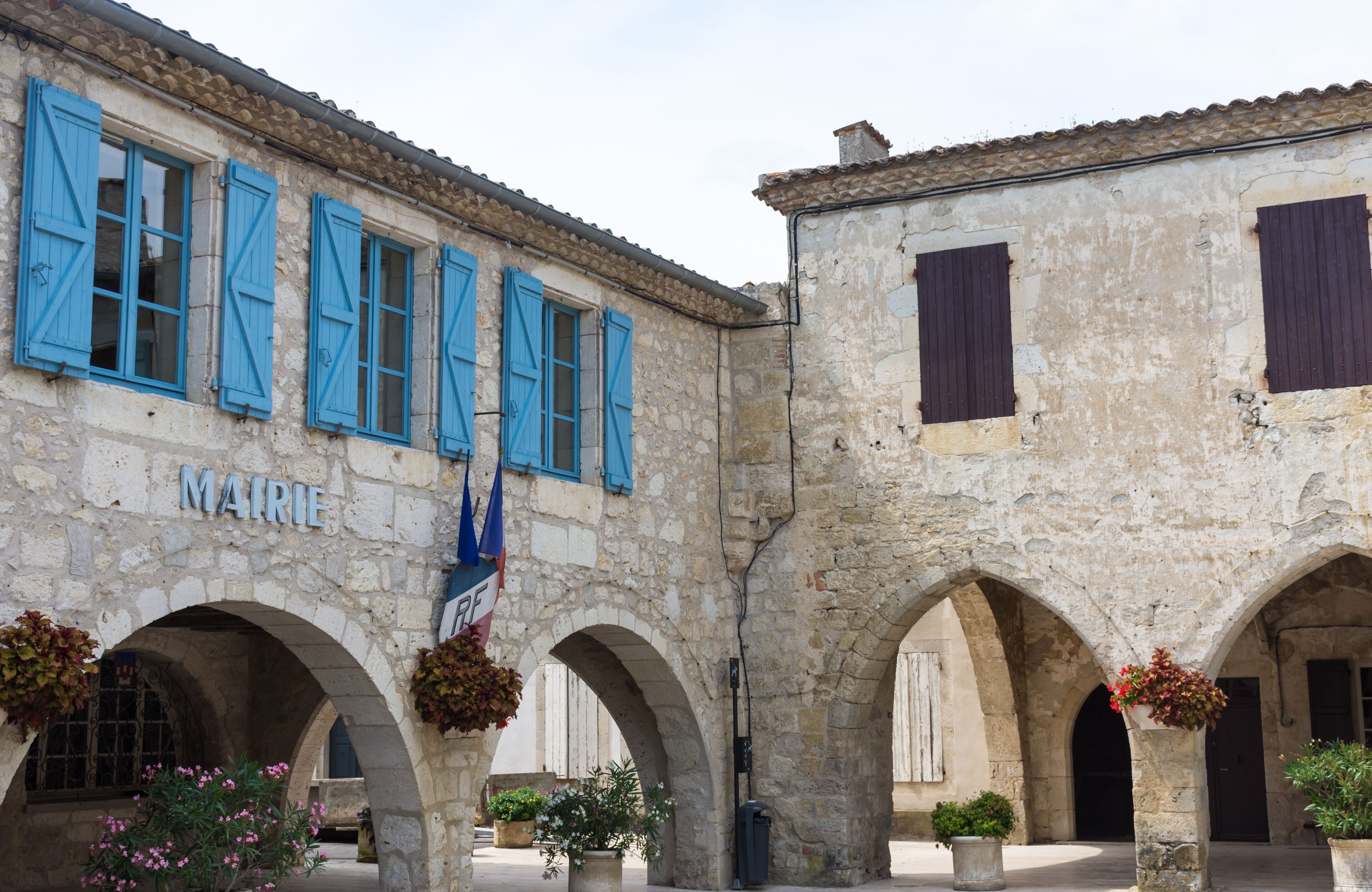 A historic stone building with blue shutters and arches.