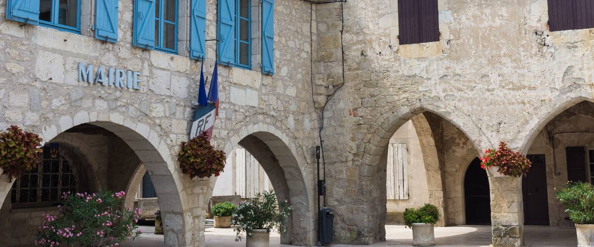 A historic stone building with blue shutters and arches.