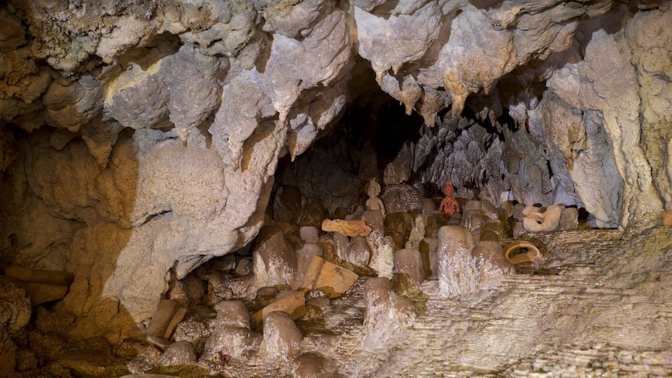 A cave with stalactites and stalagmites, and ancient statues.