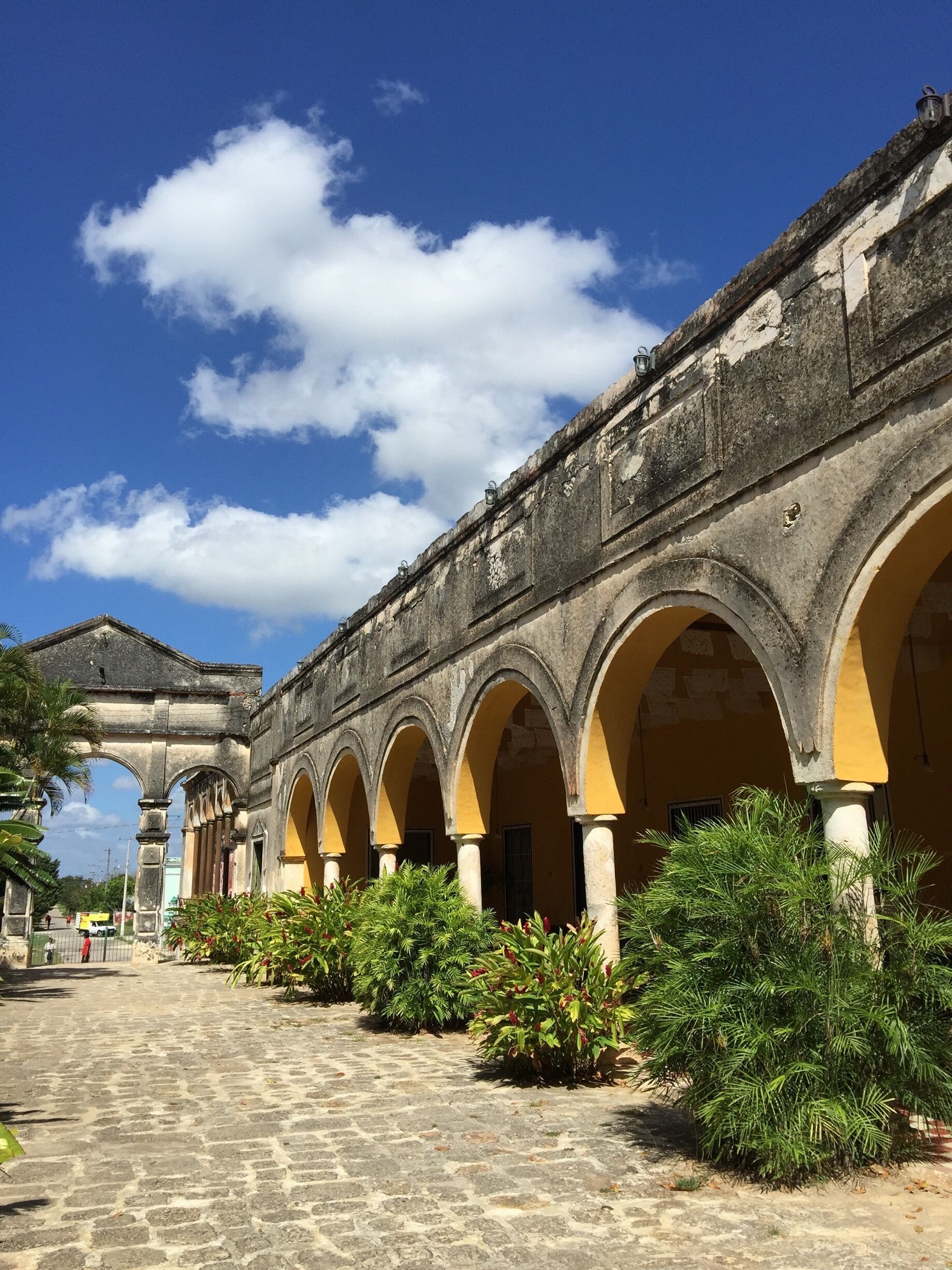 A historic building with a series of arches and a cobblestone pathway.