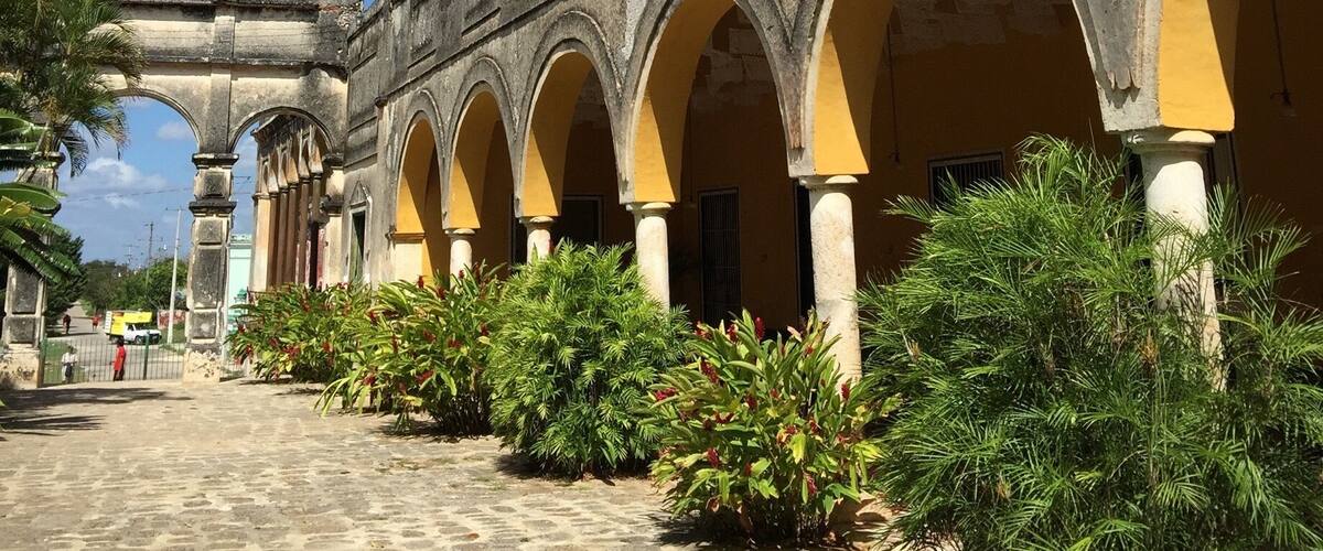 A historic building with a series of arches and a cobblestone pathway.