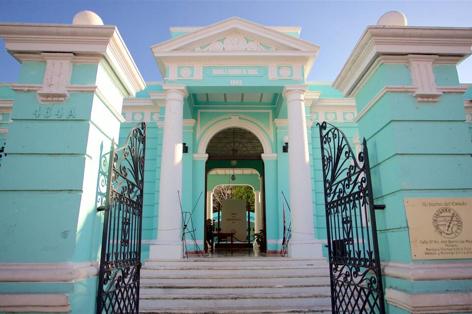 A historic building with a central archway, flanked by columns and ornate metal gates.