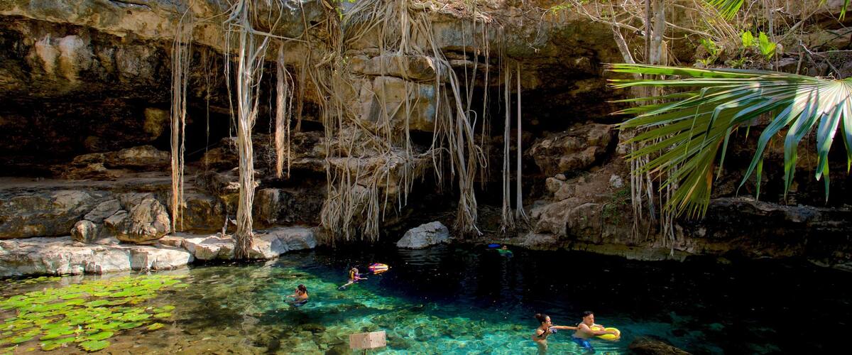 A natural pool surrounded by rocky cliffs and vegetation.